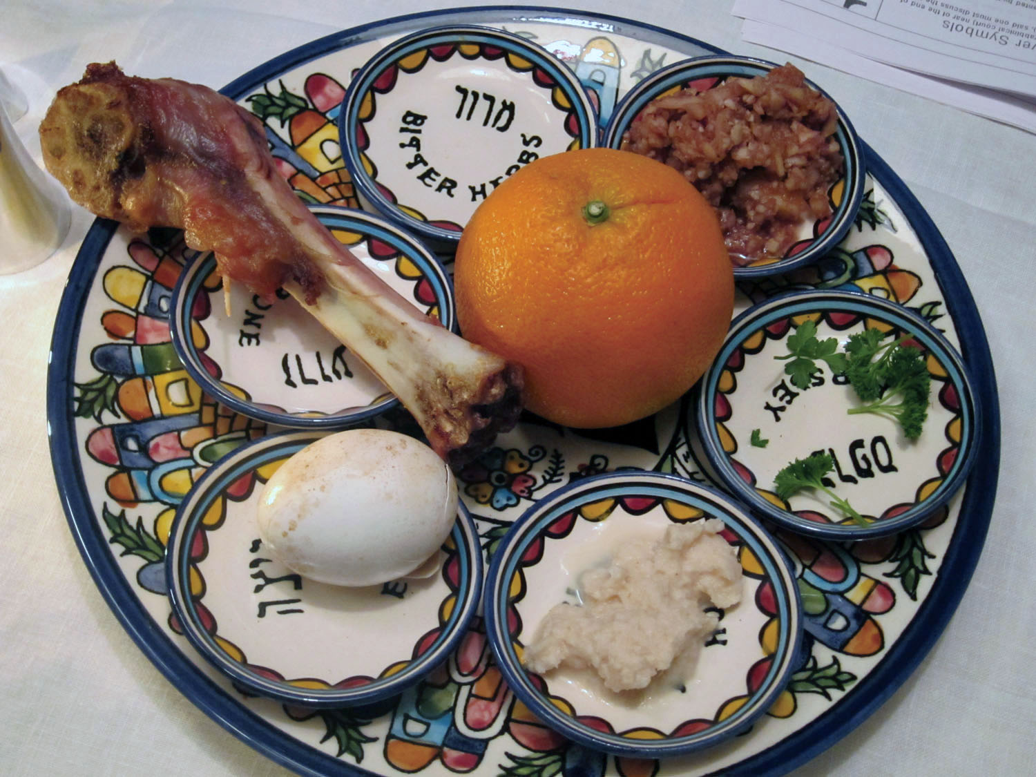 a seder plate with shank, egg, maror, haroset, parsley and and orange